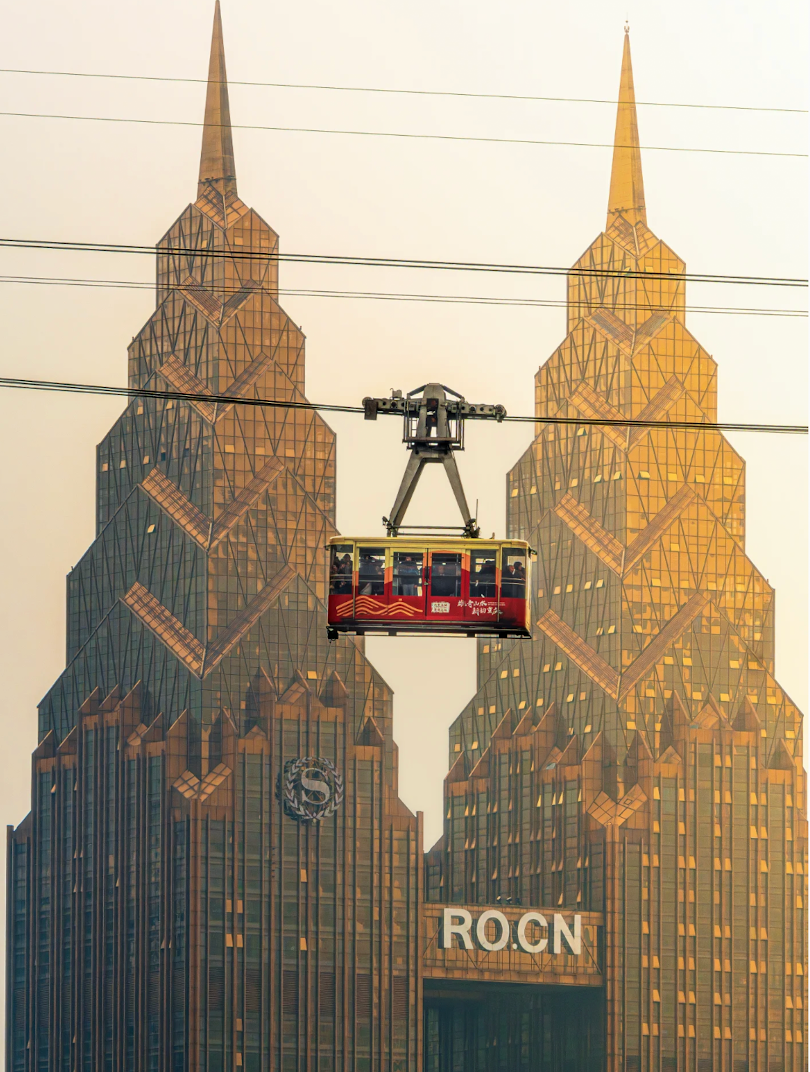 Chongqing cable car suspended between golden towers at sunset
